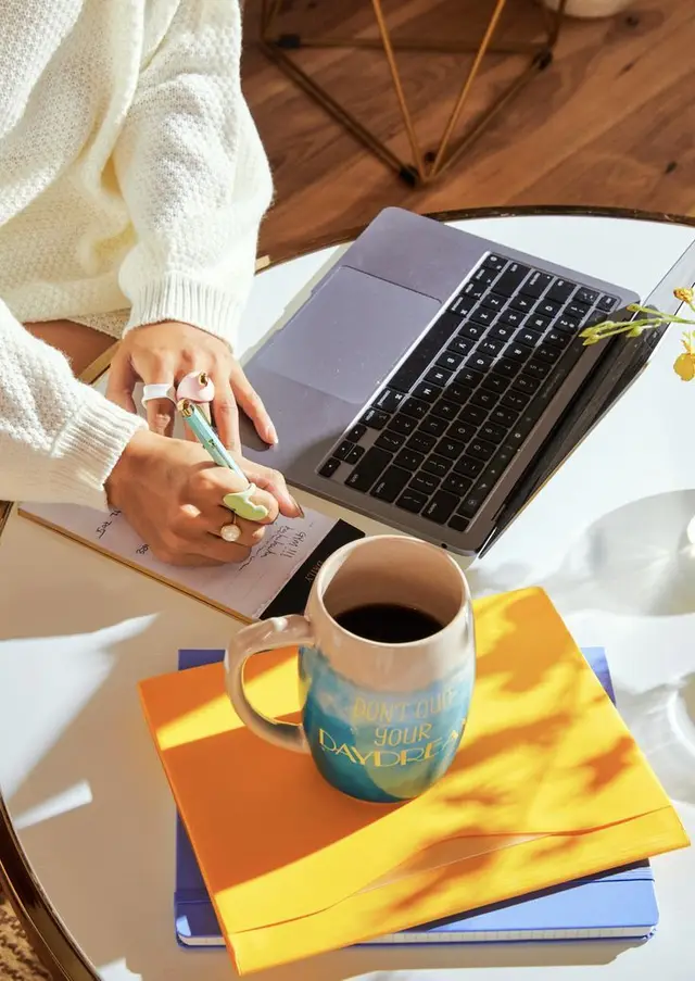 Sunlit cozy workspace with motivational mug and notebooks