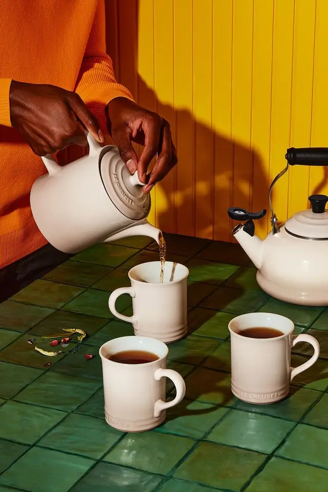 Le Creuset stoneware mugs and teapot — tea pour on green tile with yellow backdrop