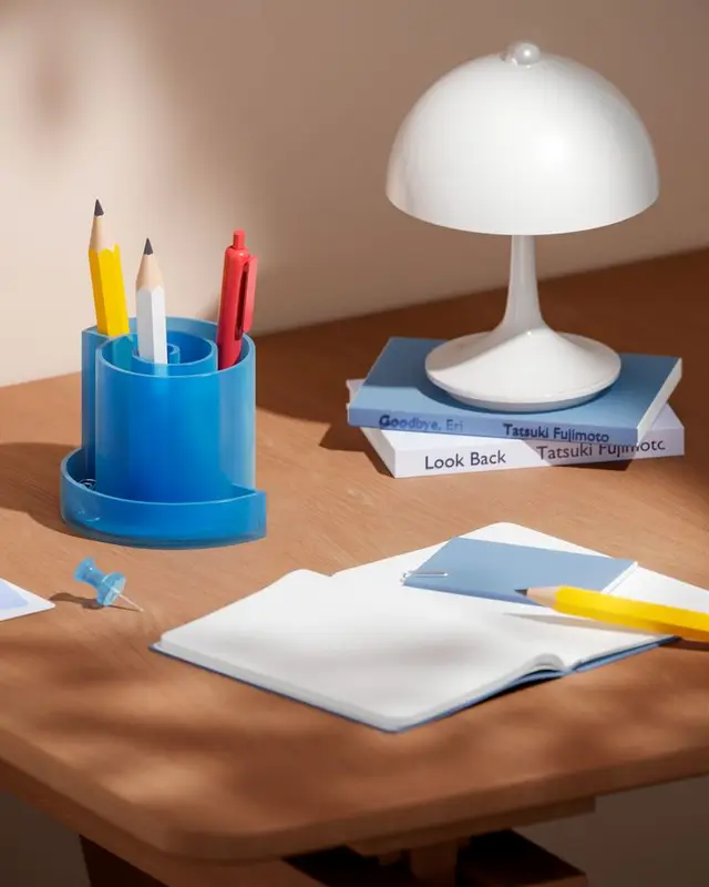 Sunlit desk still life with blue stationery holder and white dome lamp