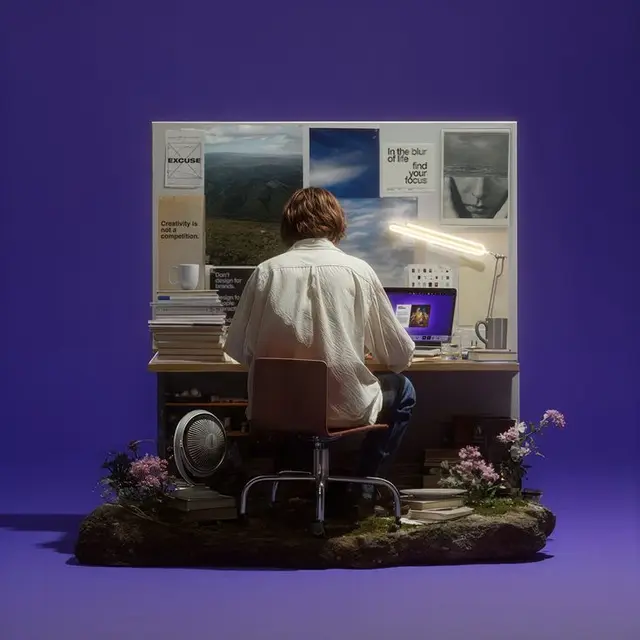 Studio diorama: person at desk with moodboard, laptop and lamp on purple backdrop