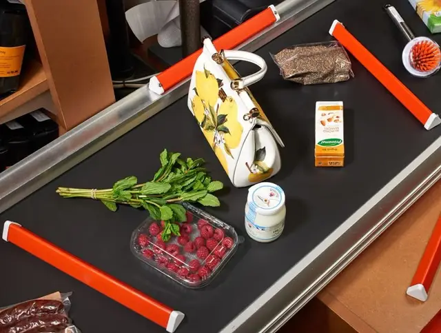 Checkout conveyor with lemon-print handbag, raspberries, mint and dairy items