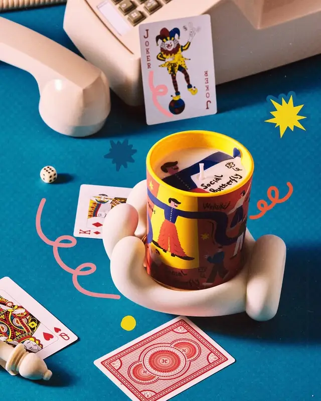 Ceramic hand holding circus tin labeled 'Social Anxiety' with playing cards and retro desk