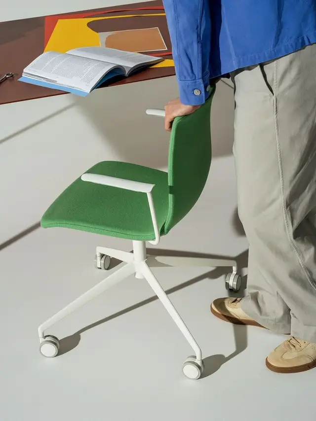 Green upholstered task chair with white caster base in minimalist workspace