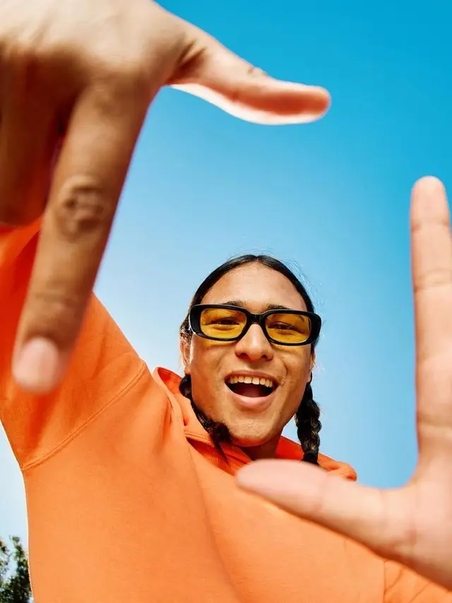 Low-angle portrait — orange hoodie with yellow-tinted sunglasses