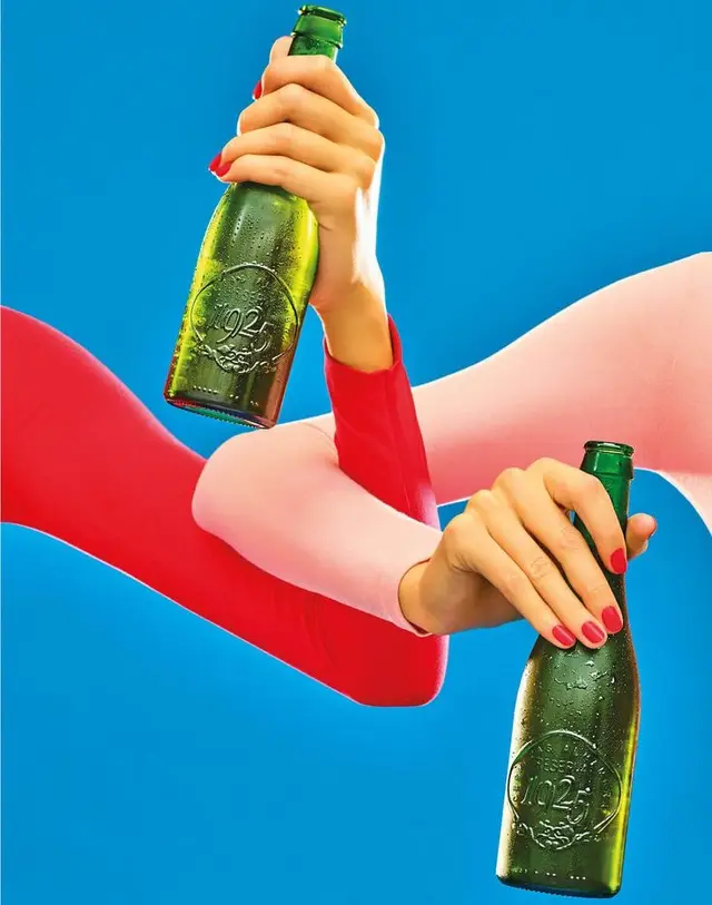Pop‑art product shot: two hands holding green embossed bottles