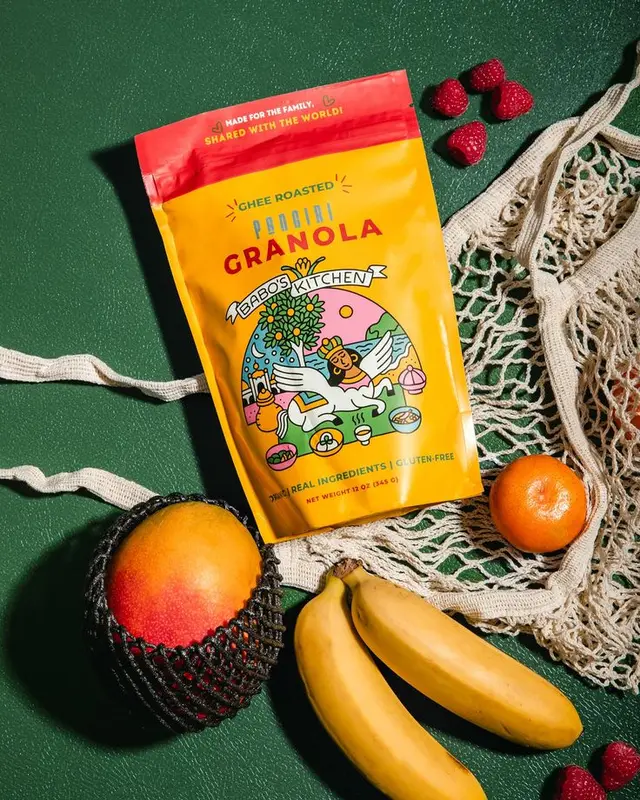 Babo's Kitchen Ghee-Roasted Granola — yellow pouch flat-lay with mango and bananas
