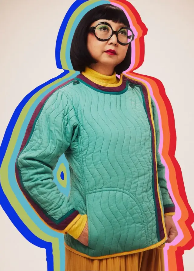 Turquoise quilted jacket with layered rainbow silhouette — studio fashion portrait