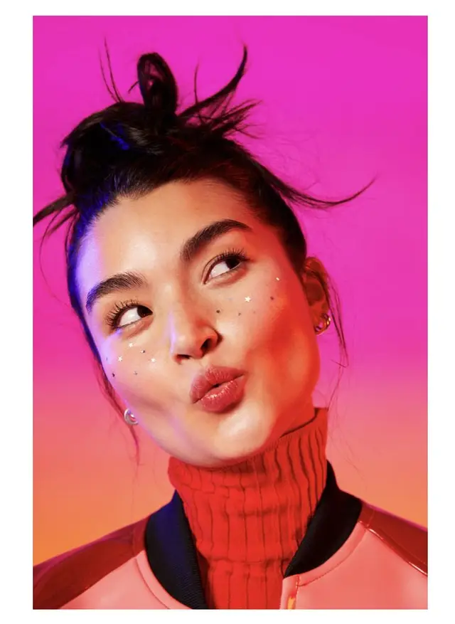 Vibrant editorial portrait with star face stickers and pink gradient backdrop