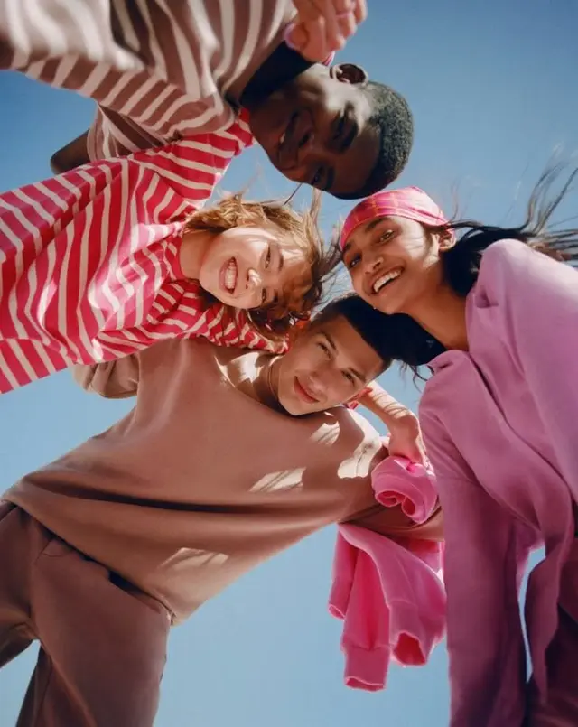 Worm's-eye portrait of four young people in pastel streetwear
