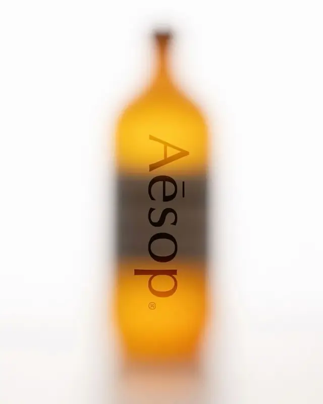 Aesop amber glass bottle — blurred minimalist still life