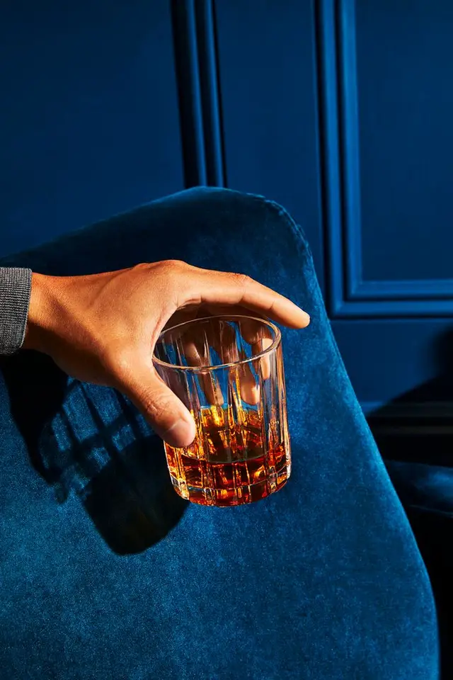 Cut-crystal whiskey glass on navy velvet chair